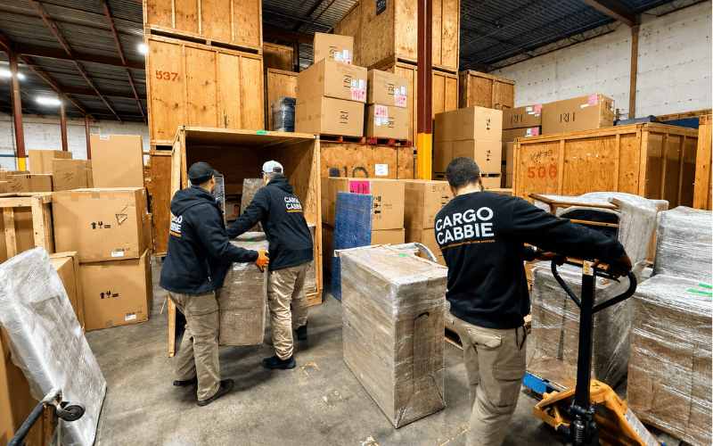 CARGO CABBIE team moving wrapped items into wooden storage crates at the Toronto warehouse